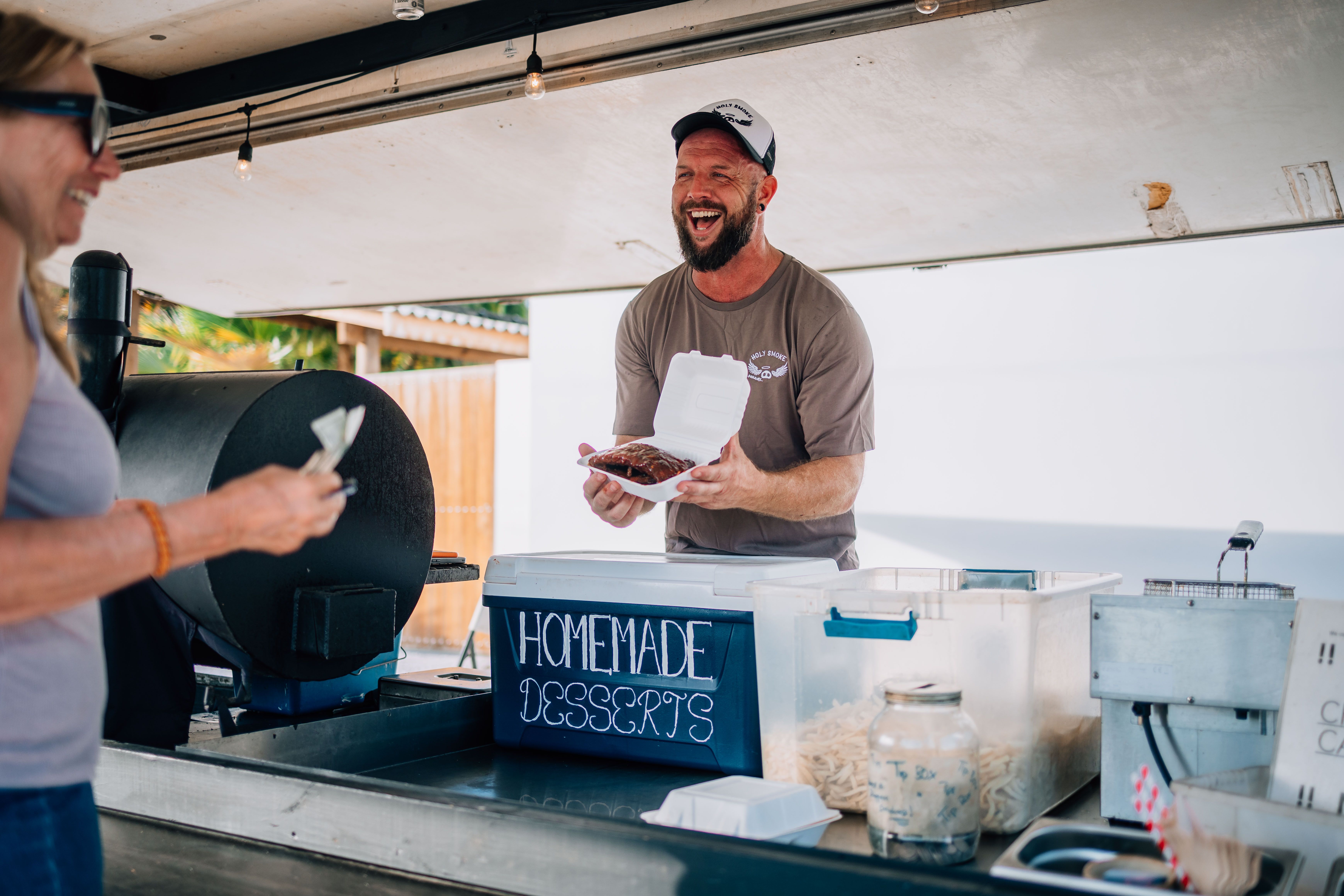Happy guests leaving Holy Smoke Bonaire with takeout BBQ